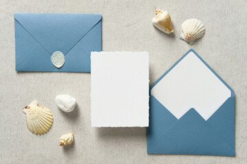 Nautical wedding invitation card mockup and blue envelopes with seashells on pastel beige...