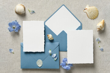 Nautical wedding invitation cards and blue envelopes with seashell and flowers on beige background....