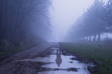 A ghostly figure reflected in water in the countryside