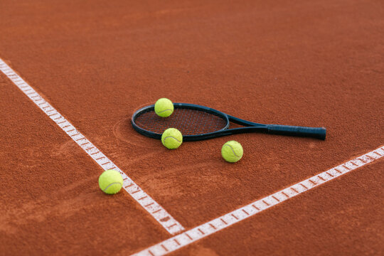 Tennis racquet on a court with tennis balls