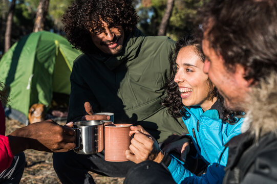 Happy diverse hikers clinking mugs of tea