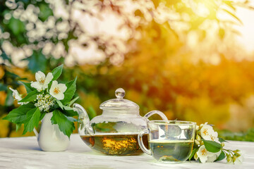 Philadelphus or garden jasmine flowers, healthy herbal tea cup of hot tea. Romantic dinner with therapeutic fragrant tea.