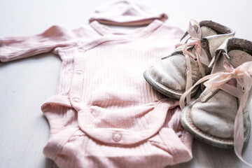 pink newborn babygirl body dress together with rustic small shoes with pink laces. First born child and pregnancy concept.