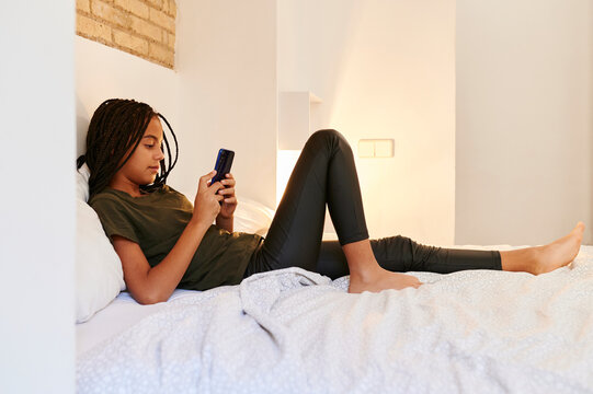 Girl lying on her bed using a cellphone