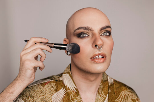 Young man applying makeup on face