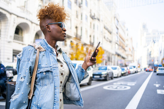Black Woman With Phone Crossing The Street In The City.