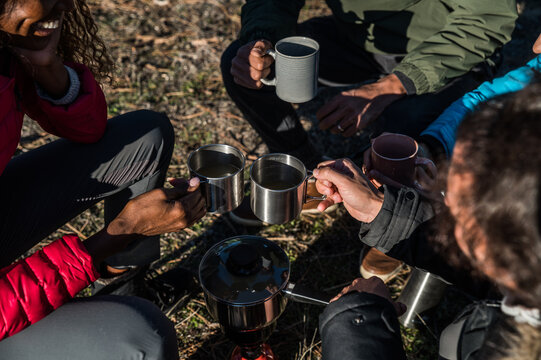 Happy diverse hikers clinking mugs of tea