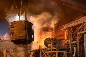 A metallurgical ladle filled with molten metal bucket is suspended on a special crane beam