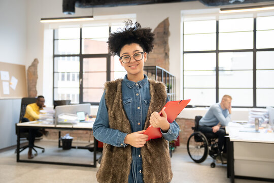 Woman Holding Folder And Smiling At Office