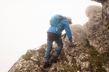 Senior hiker climbing to the summit