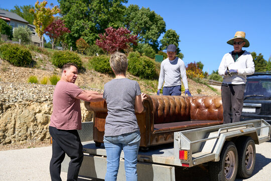 Friends help lift sofa onto trailer