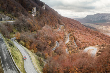 Red car on a curvy road during autumn
