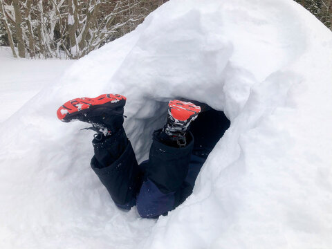 Funny winter games, legs of red-soled boots sticking out of a winter object, humor concept.
