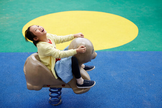 Asian girl, happy to play with animal spring chair



