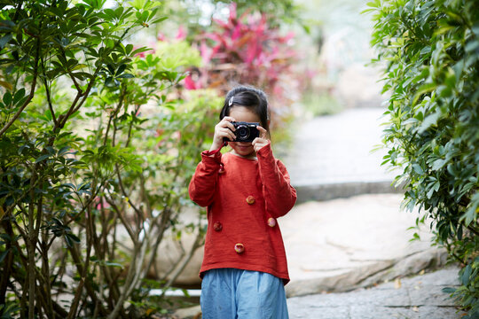 Cute Asian little girl holding a camera to shoot