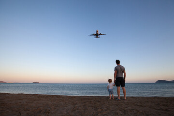 Obraz premium beach travel, father and child looking at airplane
