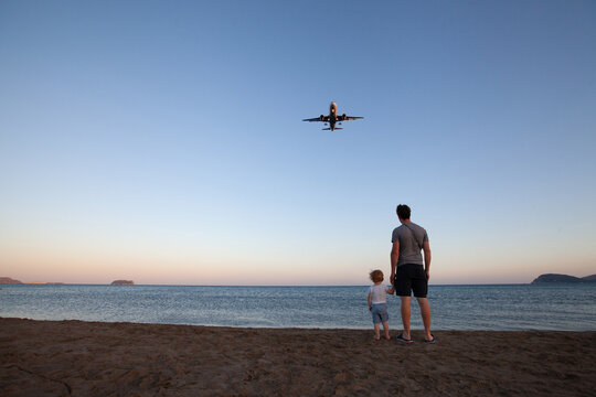 beach travel, father and child looking at airplane