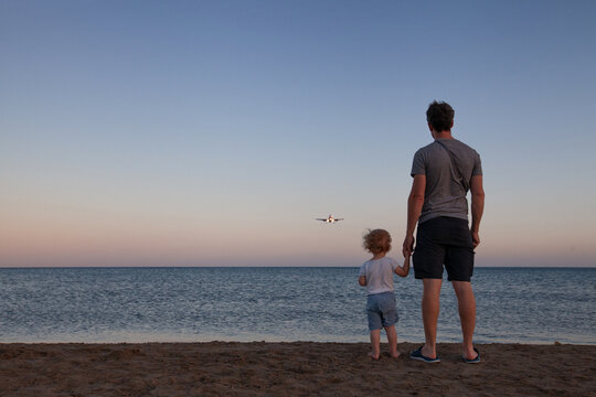 father and child looking at airplane, travel