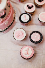 A festive table setting with a lot of sweets: muffins, cupcakesetc. for celebrating of first Birthday of little girl. Candy bar. Birthday party