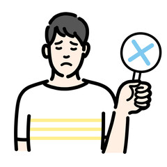 バツの札を持って残念そうな表情の若い男性のバストアップ