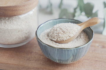 Psyllium husk in wooden spoon and bowl on wooden plate, superfood fiber prebiotic food for gut...