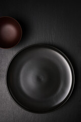 empty black plate and a cup on a slate surface, food photography background or backdrop, top view with copy space 