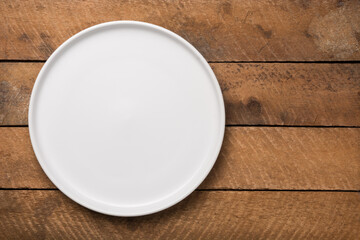 empty white plate on a wooden table top, food photography background or backdrop, horizontal top view with copy space  - Powered by Adobe