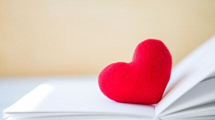 Red heart on book with space on blurred background, valentine day background idea, selective focus