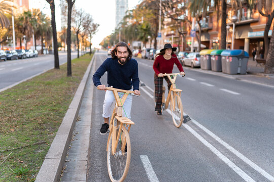 Playful man riding wooden bicycle with girlfriend