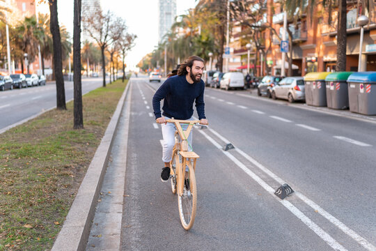 Joyful man riding wooden bicycle on bikeway