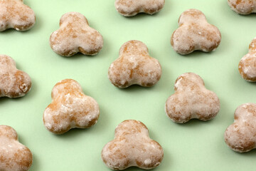 Glazed mint gingerbread cookies in rows on light green background