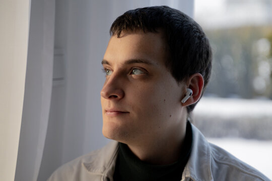 Man Looking Through Window With AirPods In His Ears 