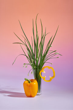 Orange bell pepper lying on the table near garlic chives 