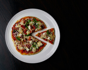 Fresh pan vegetable pizza served on white platter with a black background