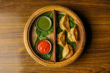 Steamed Dumplings / Momos served with red and green sauce in a wooden tray