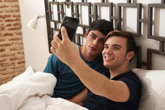 Portrait of a gay couple in bed taking a selfie