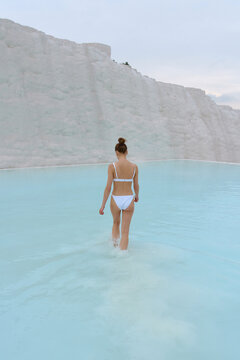 a girl walks in a swimsuit on the water of a beautiful azure color