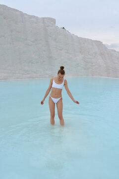 a girl walks in a swimsuit on the water of a beautiful azure color