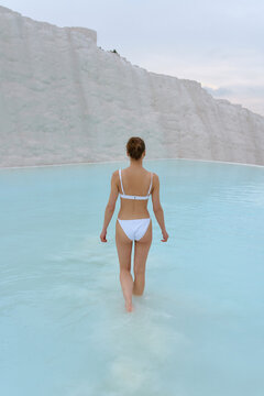 a girl walks in a swimsuit on the water of a beautiful azure color