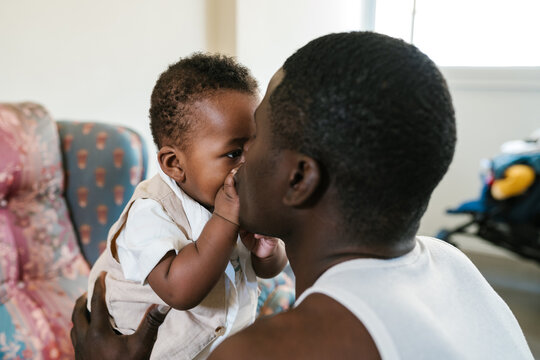 Black baby kissing father at home