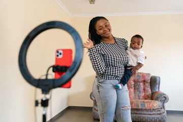 Smiling mother with son waving to camera of smartphone