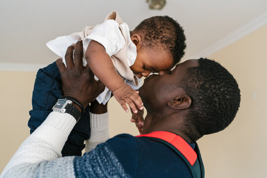 Black dad lifting and kissing baby