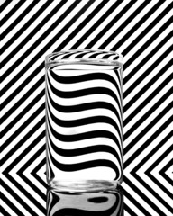 A glass filled with water with a black and white pattern background