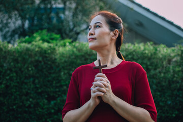 Asian woman praying with wood cross and believe in God