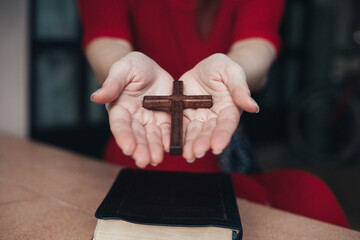 Woman hands praying to god with wooden cross
