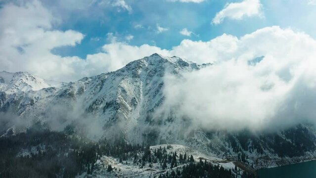 This stock video shows mountains shrouded in snow-white clouds. A beautiful mountain landscape will decorate your projects related to travel, nature, tourism, winter, mountains, weather.