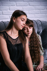 Fototapeta premium Portrait of young sisters sitting side by side on the couch. Two girls are watching a movie.