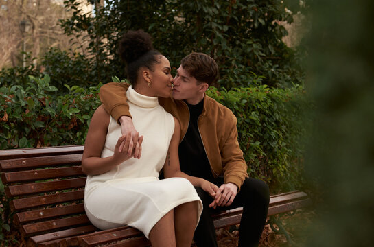 Portrait of a multiracial couple kissing at a bench
