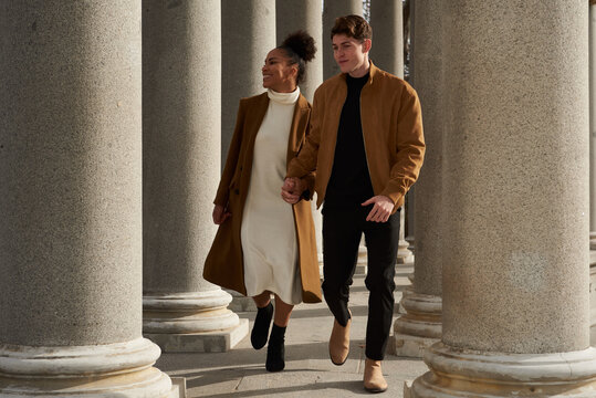 Couple running while holding hands between columns