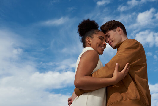 Couple hugging romantically at a blue sky